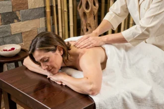 Femme recevant un massage royal dans un spa de luxe avec table en bois et drapé en lin blanc
